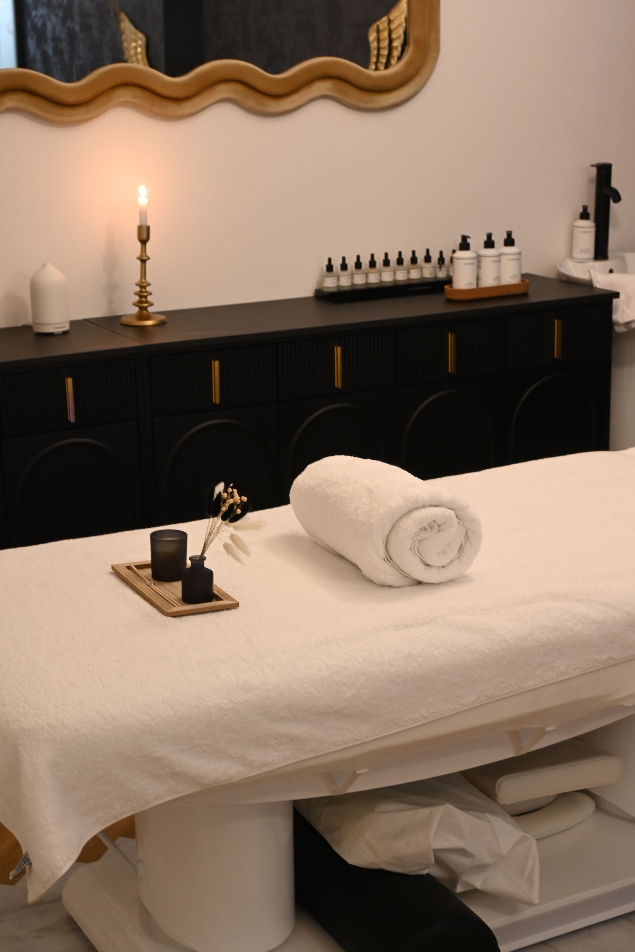 Table de massage, bougie et serviettes roulées dans une lumière feutrée
